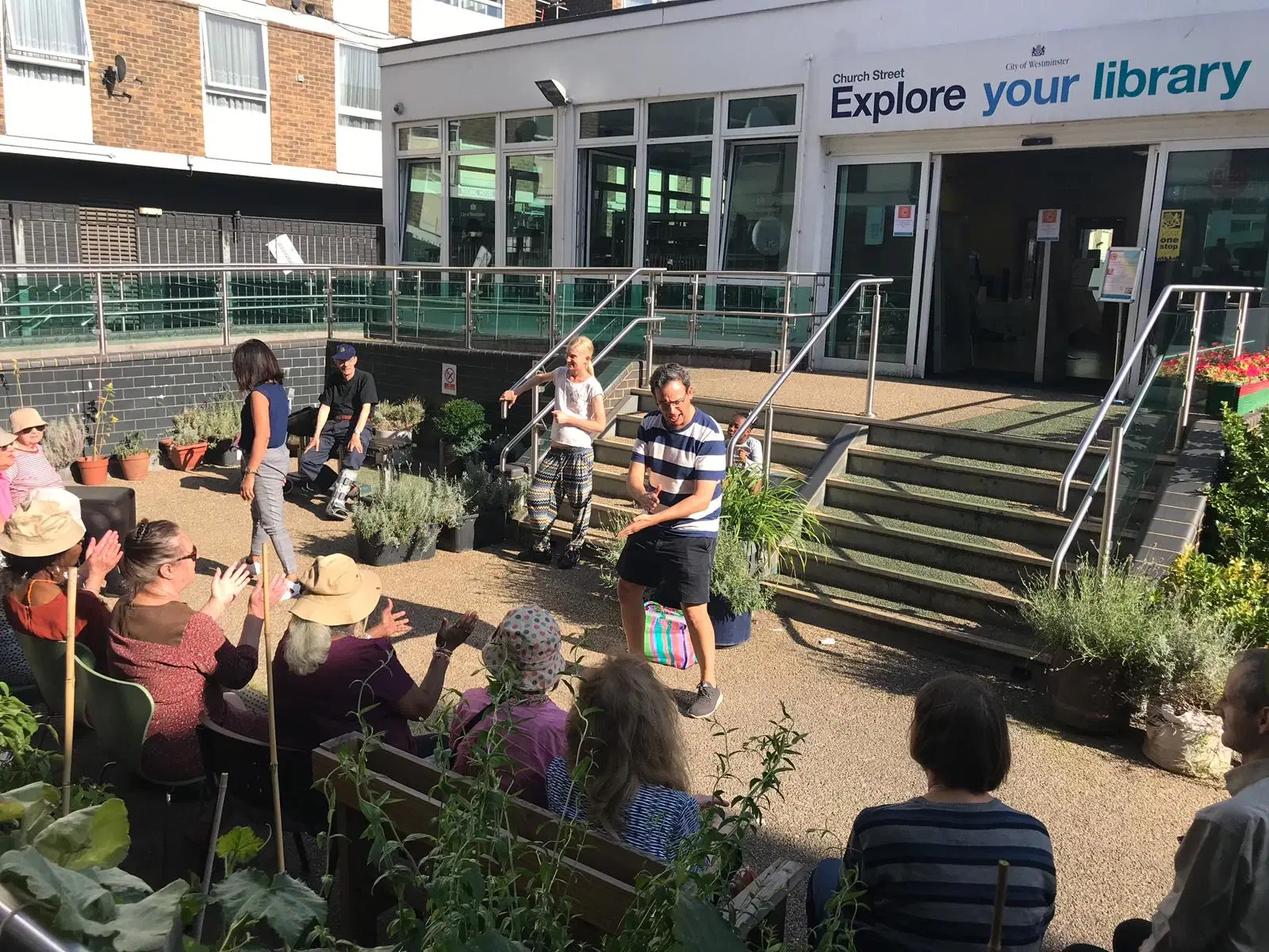 Community members enjoying a sunny day in an urban garden outside the local library.